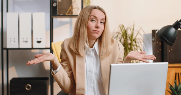 Mulher com expressão de dúvida olhando para a tela do computador, representando a frustração de não obter respostas de leads.
